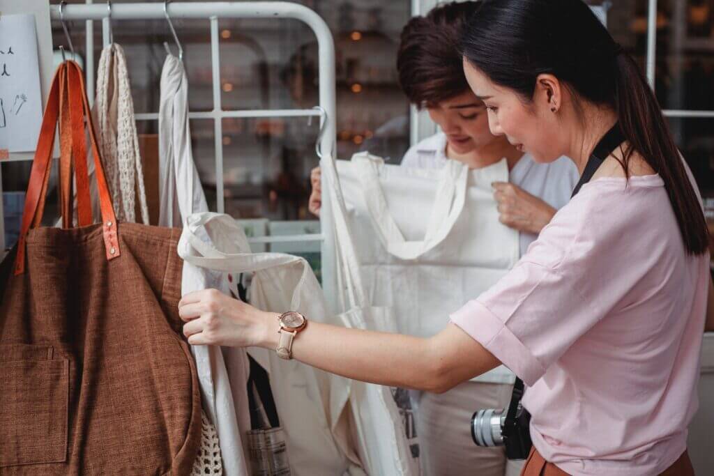 Trendy young Asian women choosing textile cotton bags in fashion boutique