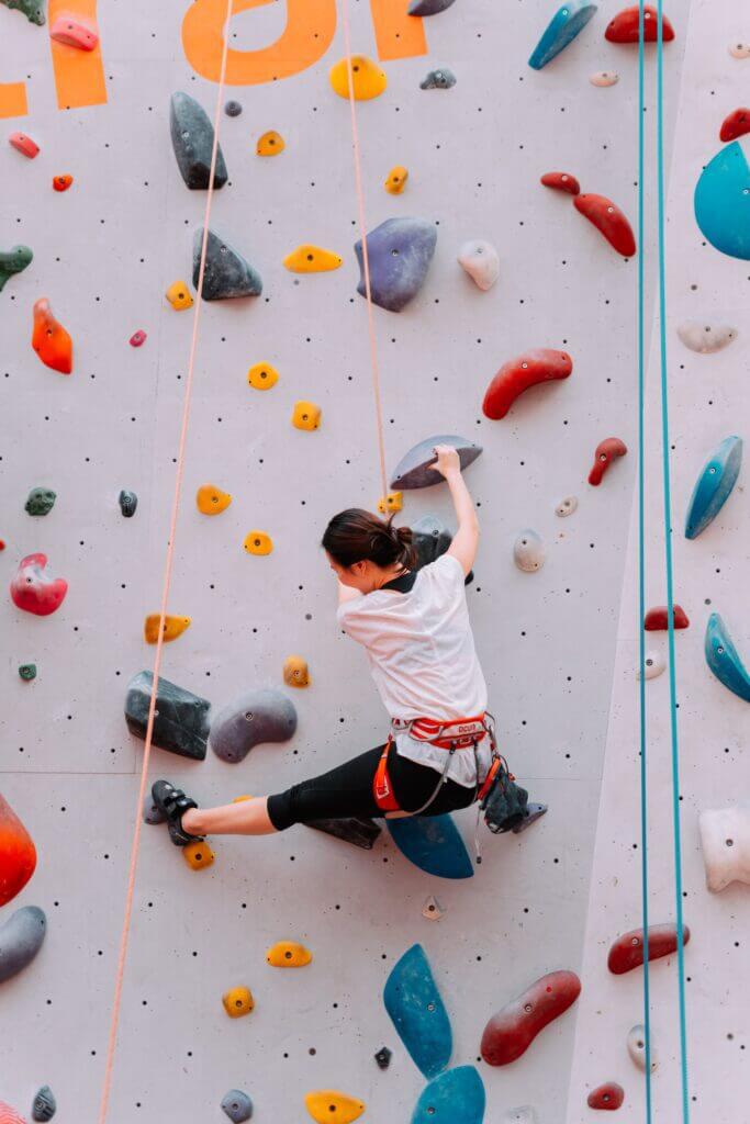 Climber wears climbing shoes, comfortable clothing, and a chalk bag while climbing indoors
 