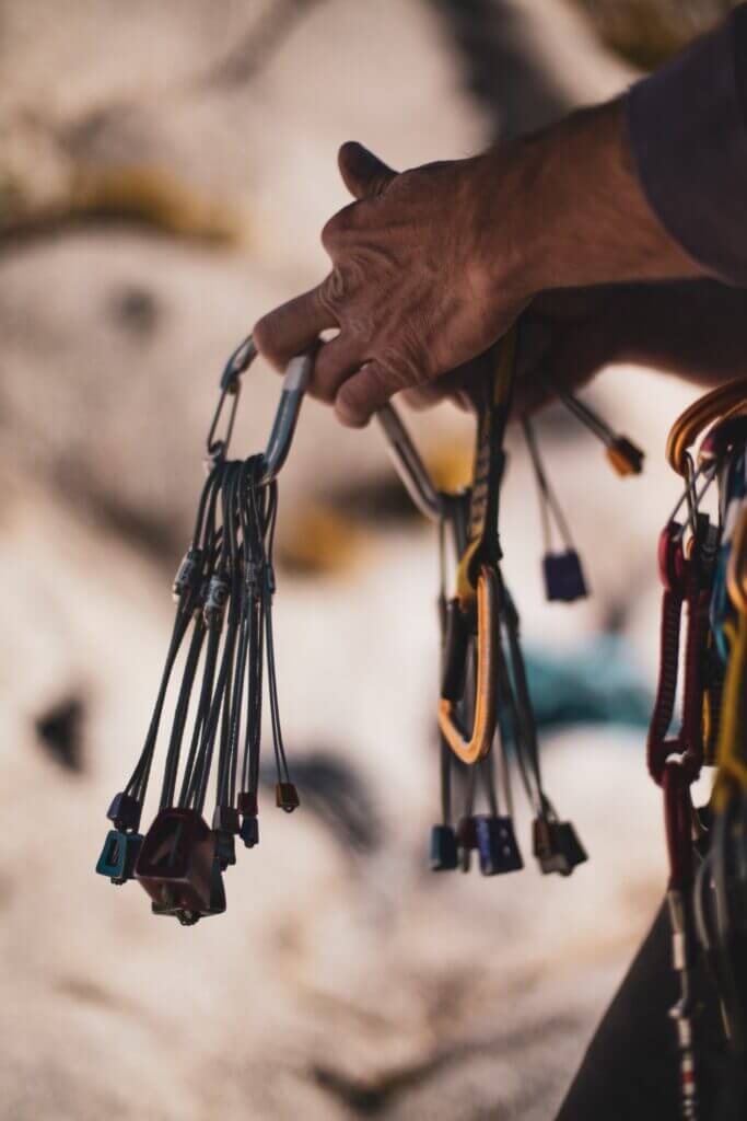 A rock climber organizes their trad climbing equipment 