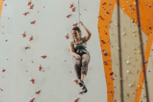 Woman wears comfortable, flexible, and breathable clothing while climbing indoors