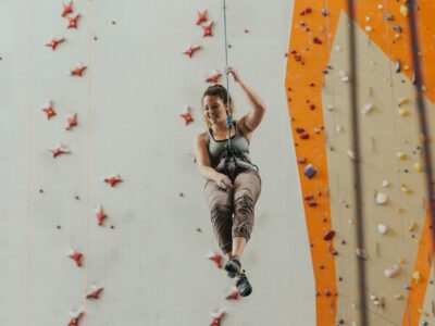 Woman wears comfortable, flexible, and breathable clothing while climbing indoors