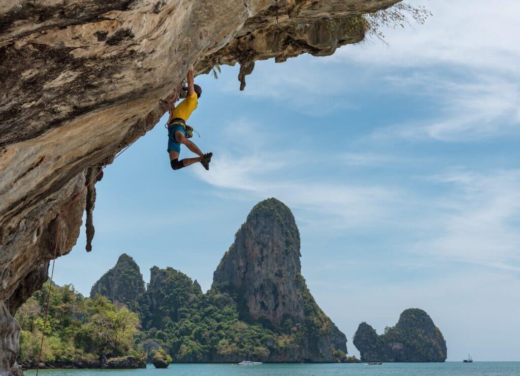 A rock climber climbs a sport route in a steep limestone cave.