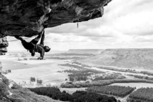 A rock climber climbs a steep roof